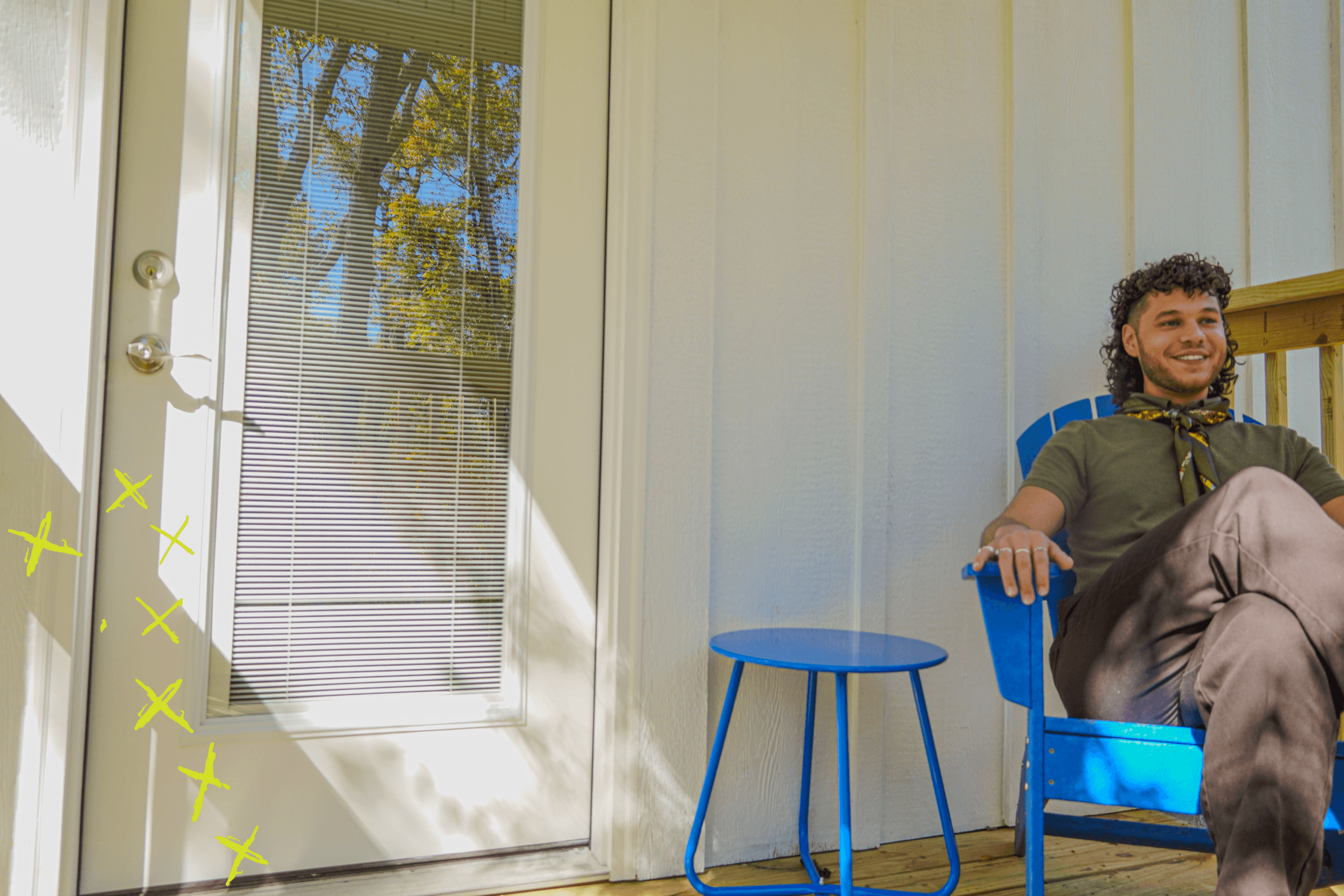 A student sitting in a blue chair on the back porch of Jack's House.
